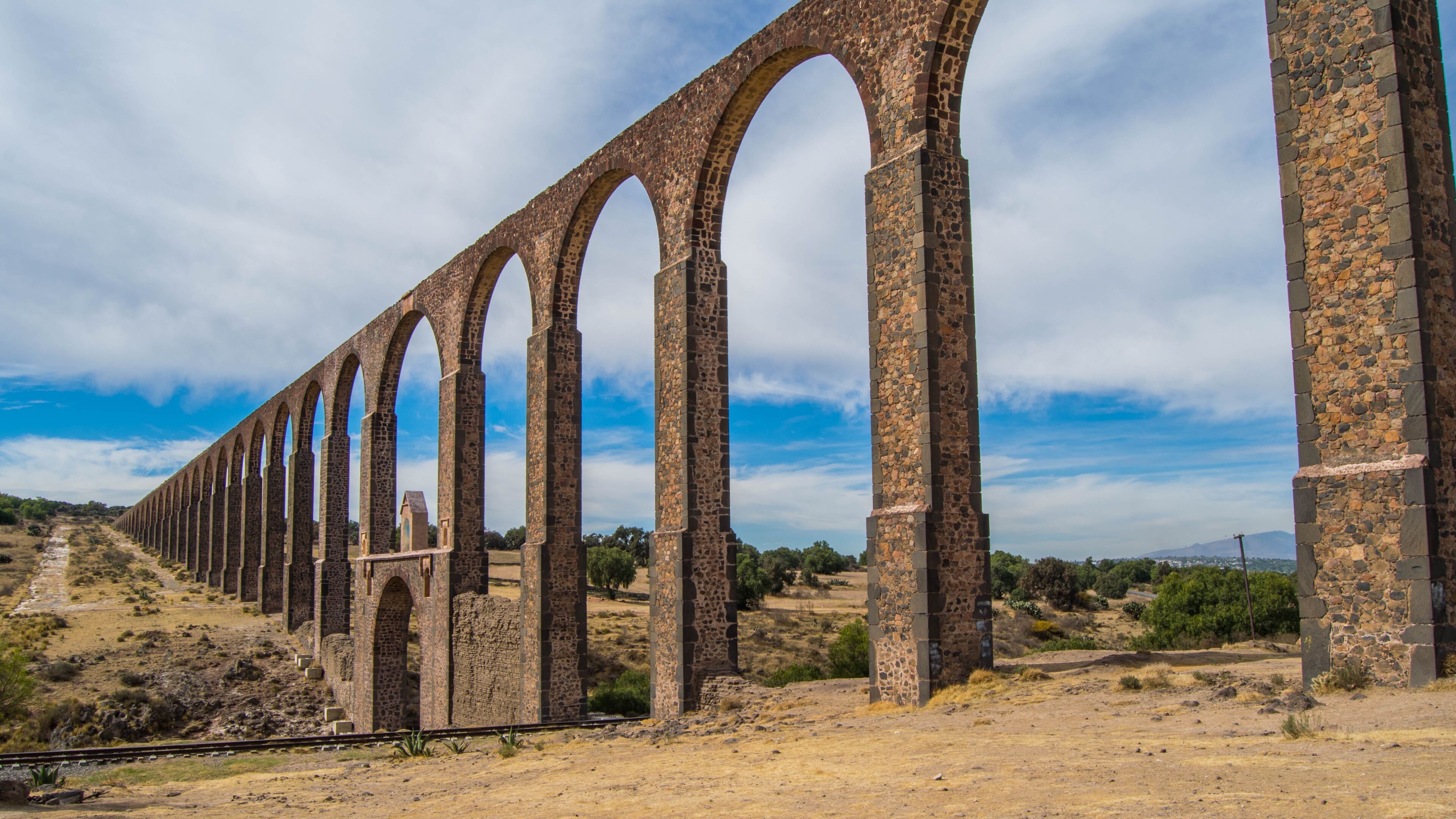A long stone viaduct with multiple arches spanning a dry, hilly landscape.
