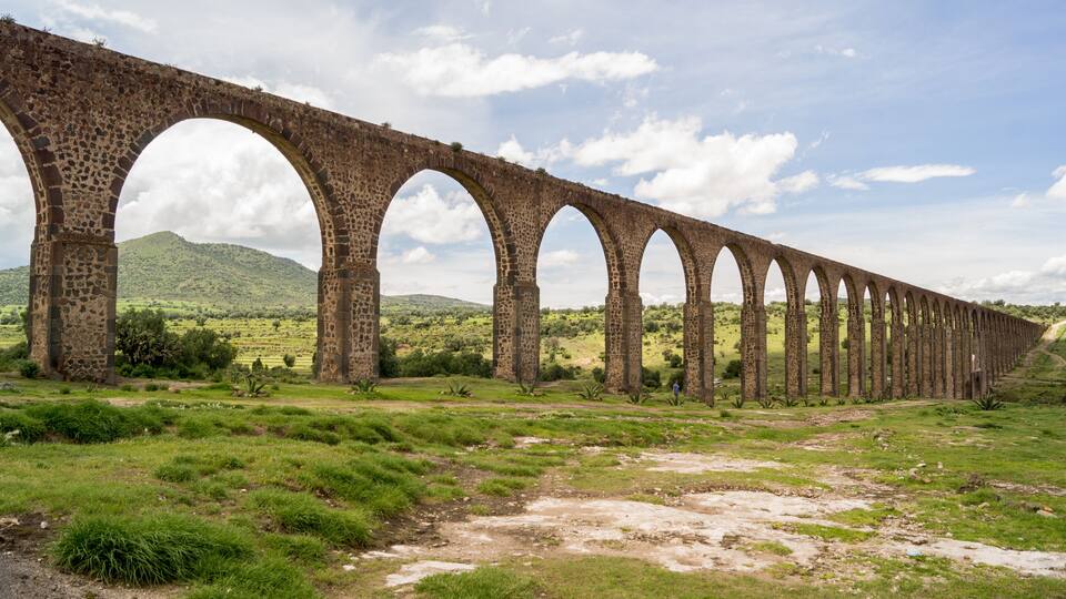 A long stone viaduct with multiple arches spanning a hilly landscape.