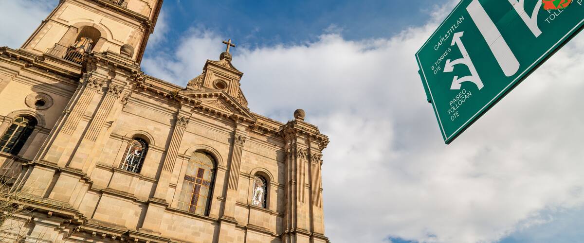A historic church with a bell tower and a street sign indicating directions to Capitulian, S. Torres, and Toloco.