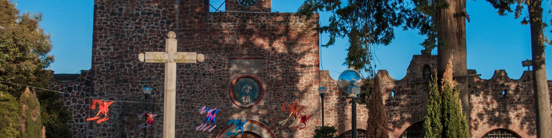 Una iglesia histórica con una gran cruz, un reloj y un campanario.