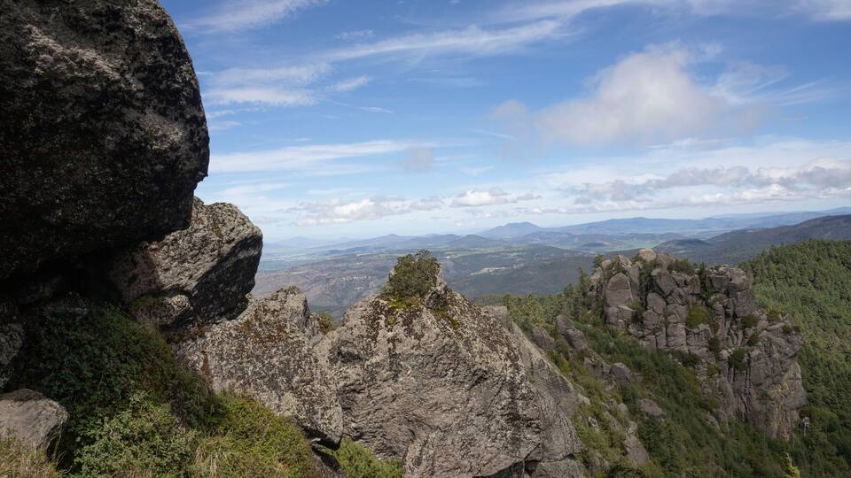 A rugged mountain landscape with prominent rocky outcrops and dense forest.