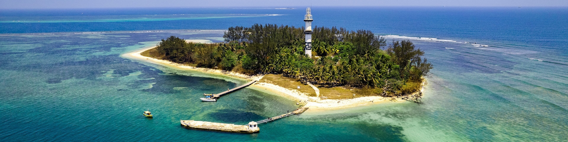 Eine Insel mit einem Leuchtturm, klarem türkisblauem Wasser und einem kleinen Steg.