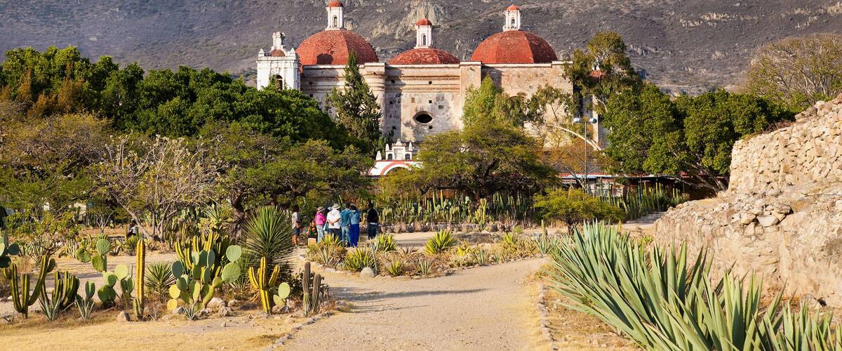 A historic building with red domes and a mountainous backdrop.