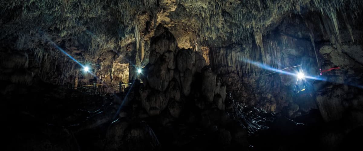 A cave with stalactites and a light source.