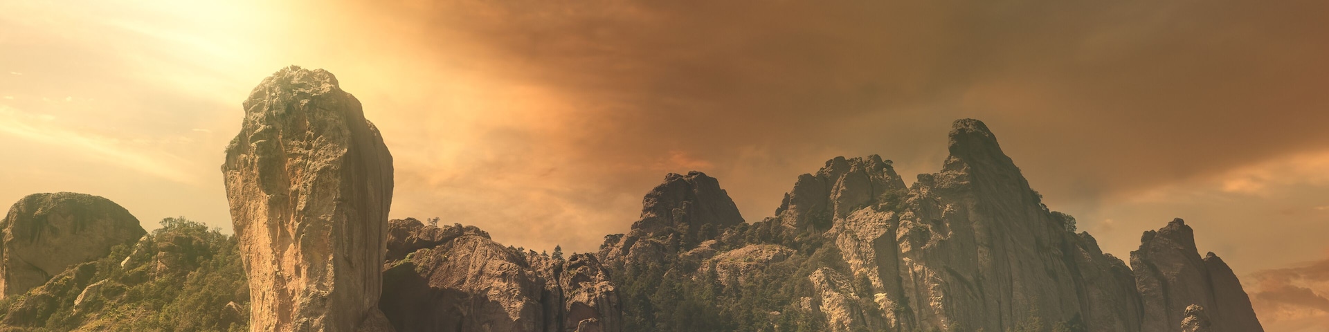 Un paisaje montañoso con formaciones rocosas destacadas y un bosque denso.