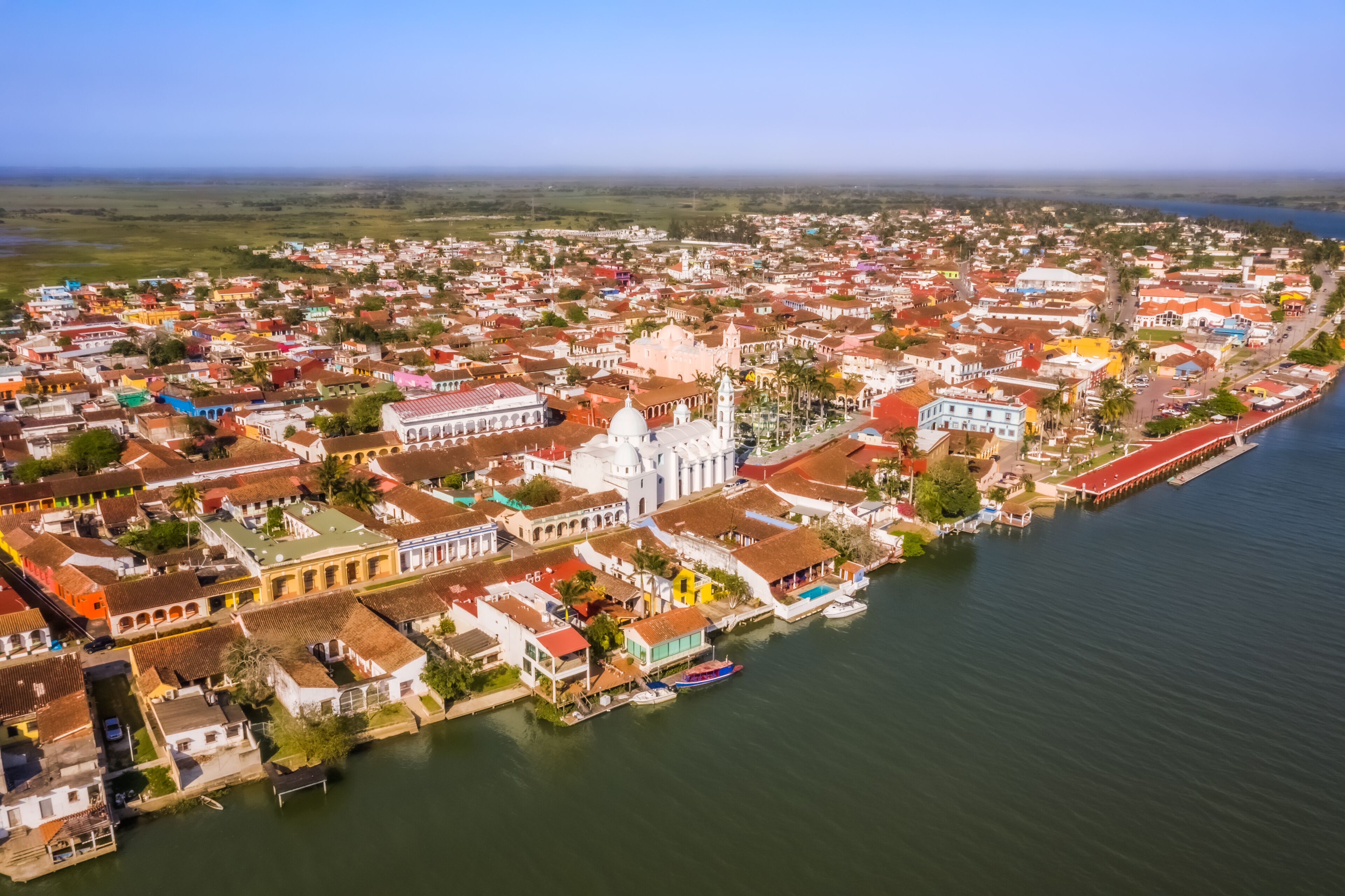 A coastal town with colorful buildings, a prominent white church, and a waterfront with boats.