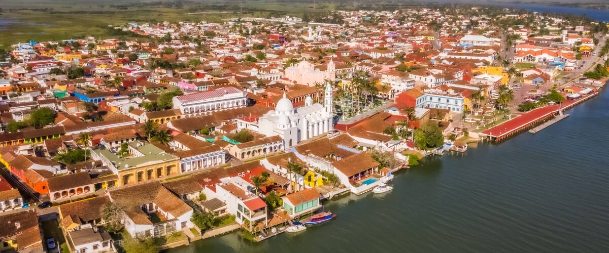 A coastal town with colorful buildings, a prominent white church, and a waterfront with boats.