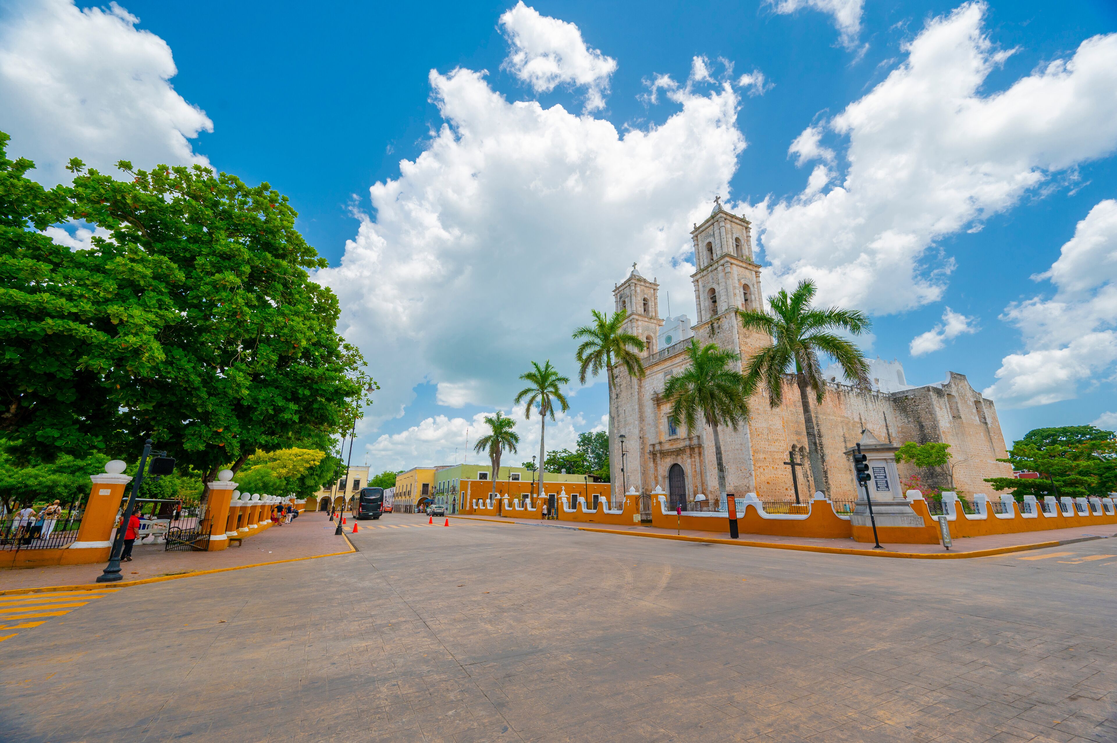 A historic church with a bell tower, palm trees, and a clear blue sky.