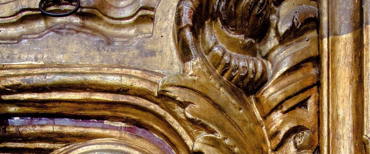 A detailed golden relief sculpture with a central spiral design and ornate leaf patterns.