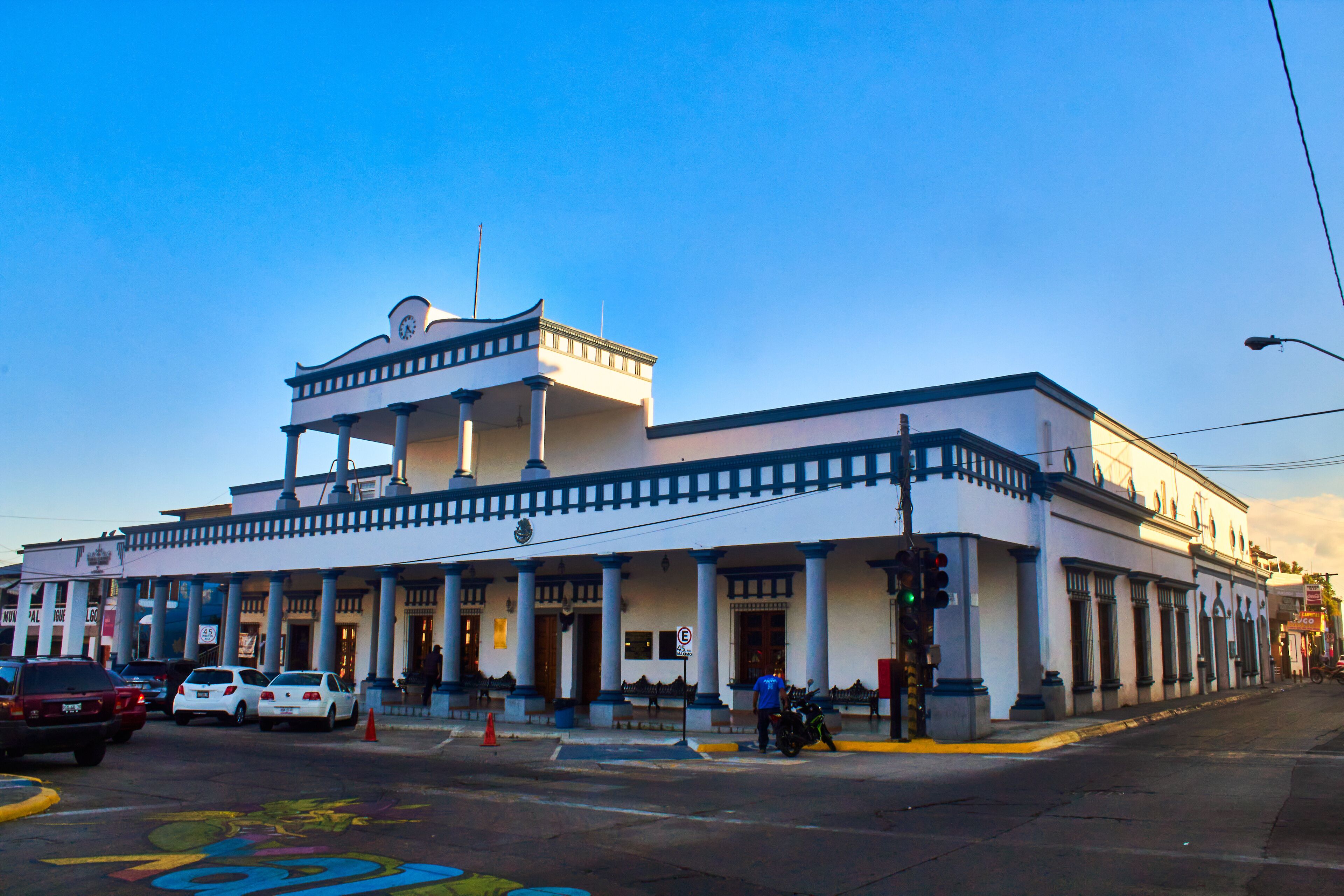 A historic building with a white facade, blue trim, and a central balcony.