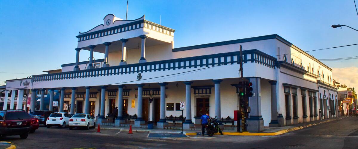 A historic building with a white facade, blue trim, and a central balcony.