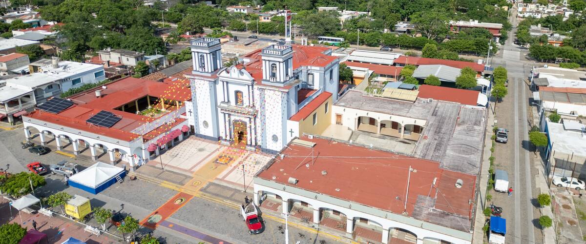 An aerial view of a town with a prominent church, a main street, and surrounding greenery.