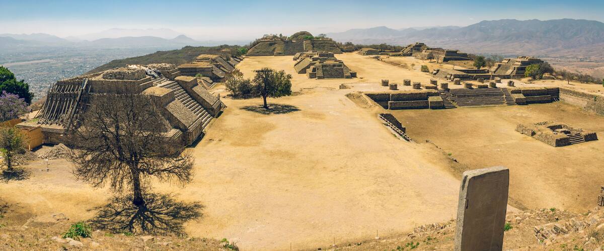 An ancient archaeological site with pyramidal structures and a large open plaza.