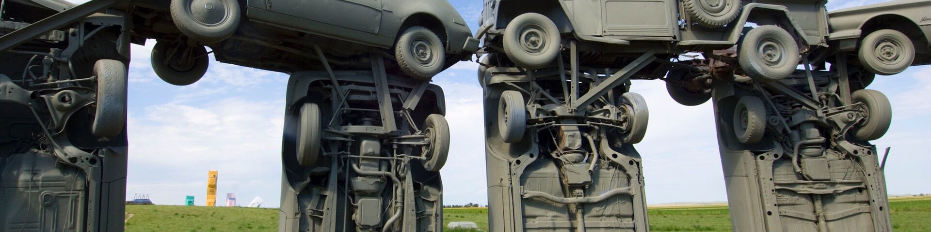 Quatro veículos militares tombados em um campo gramado sob céu claro.
