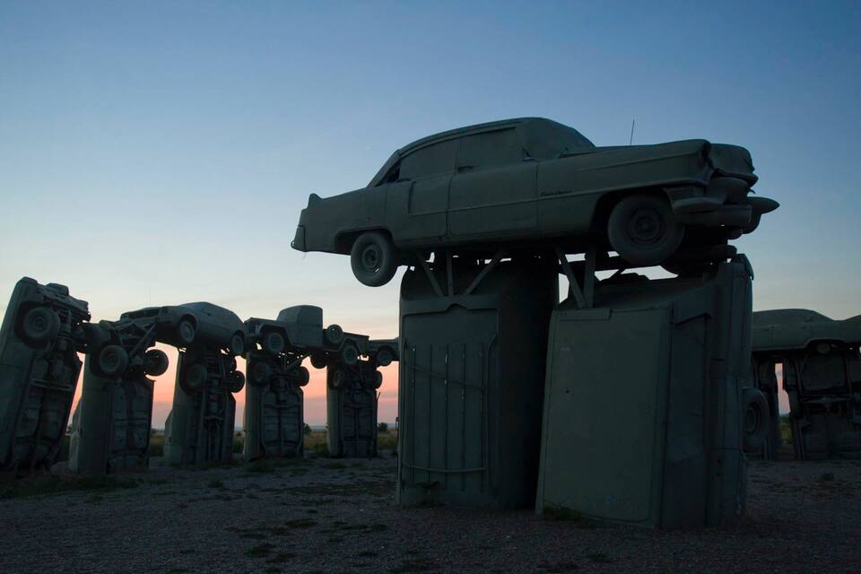 A series of military vehicles, including a car, elevated on large concrete pillars.