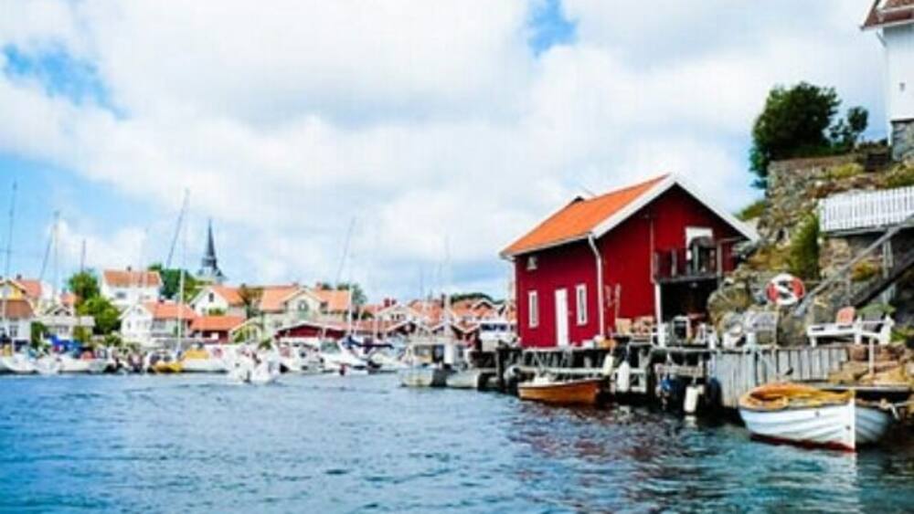 A harbor with boats, a red building, and a church.
