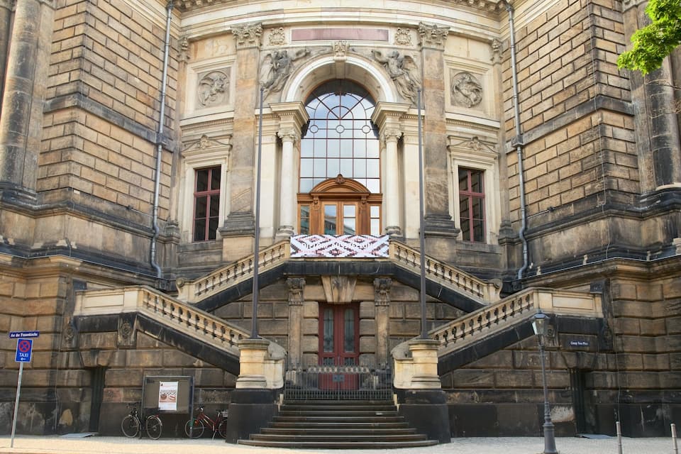 A grand building with ornate architecture, including a large arched window and a central staircase.