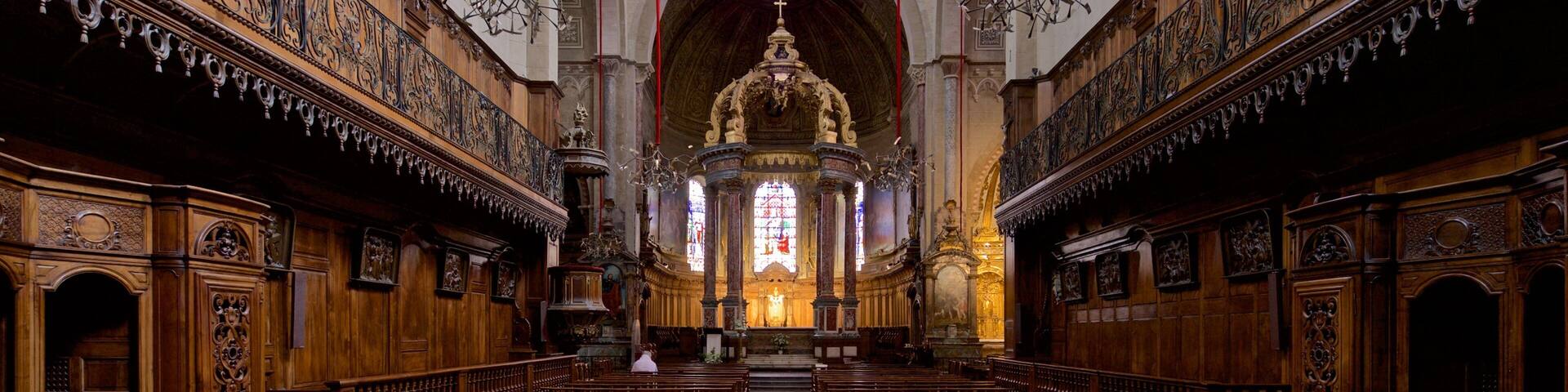 A church interior with wooden pews, ornate carvings, and a central altar.