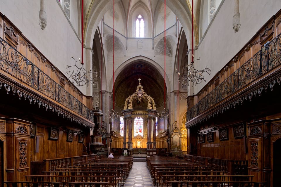 Interior de igreja com bancos de madeira, esculturas elaboradas e altar central.