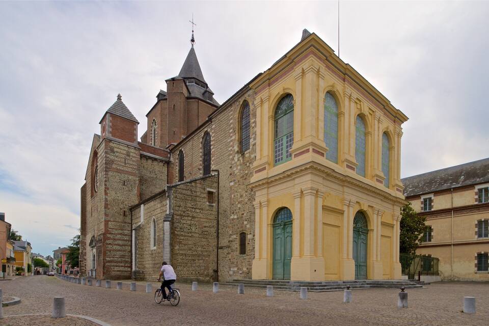 Una iglesia histórica con una torre destacada y fachada amarilla.