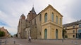 Una iglesia histórica con una torre destacada y fachada amarilla.