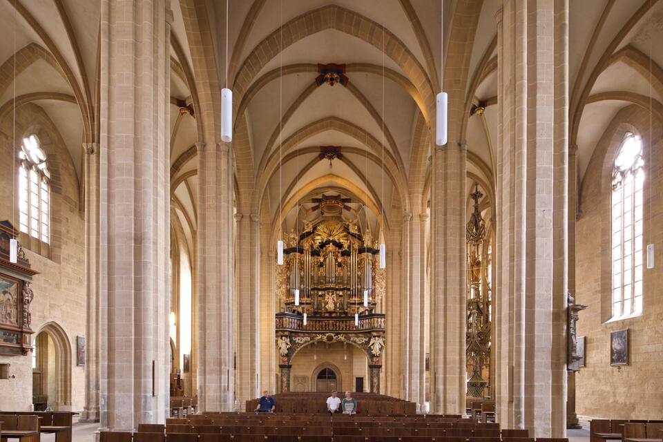 L’intérieur d’une cathédrale, avec de hauts plafonds en voûte, de grandes fenêtres à vitraux et des œuvres d’art religieux richement décorées.