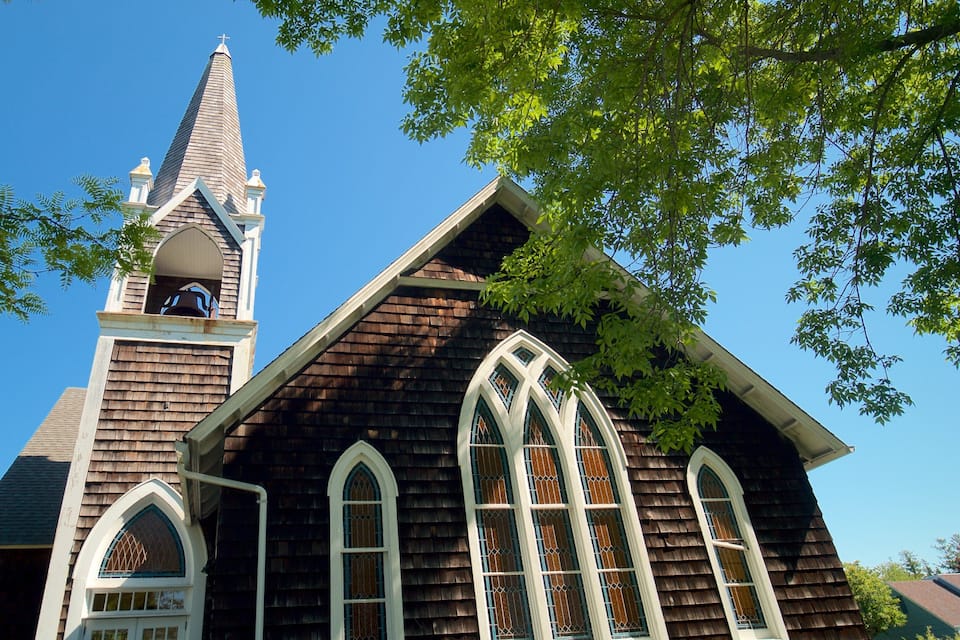 A wooden church with a steeple and arched windows.