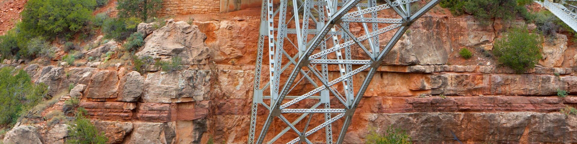 A steel bridge over a rocky cliff with sparse vegetation.