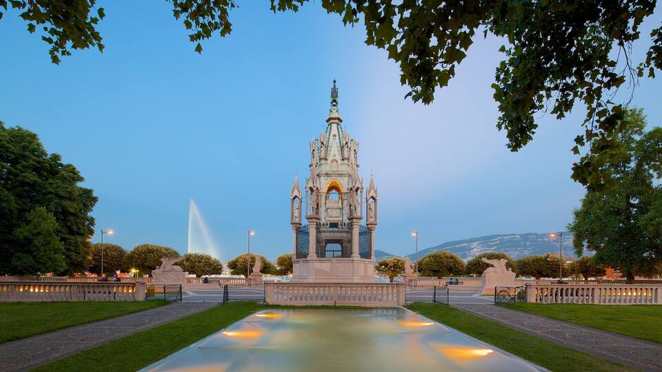 A Gothic-style monument with a spire, surrounded by a reflective pool and trees.