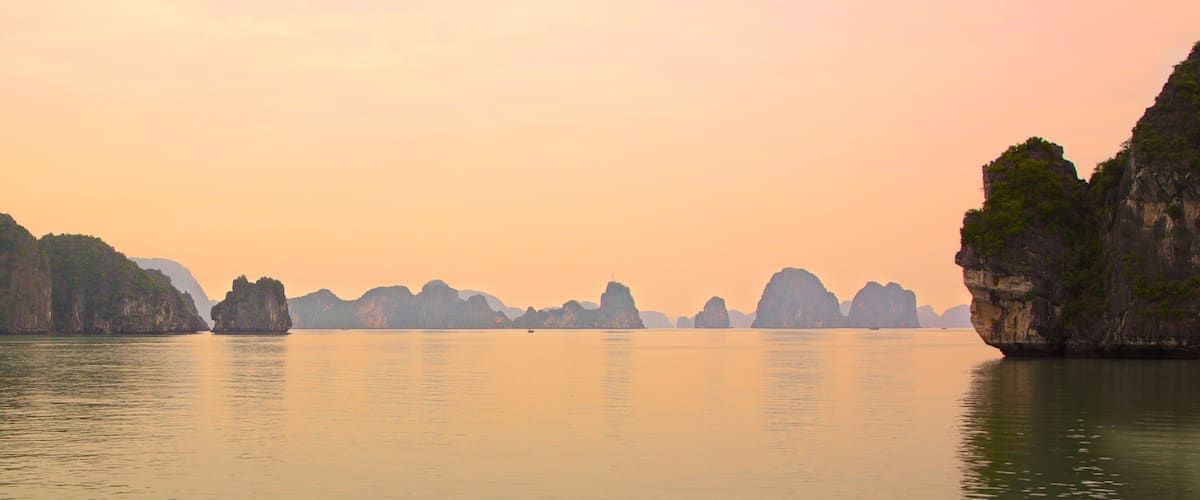 Baía de Halong que inclui imagens da ilha, um pôr do sol e paisagem