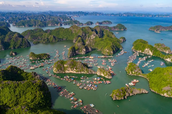 An aerial view of a coastal area with numerous small islands and a dense cluster of boats and docks.