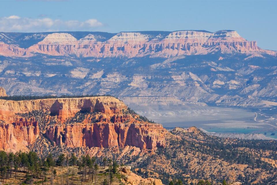 A canyon with layered rock formations and sparse vegetation.