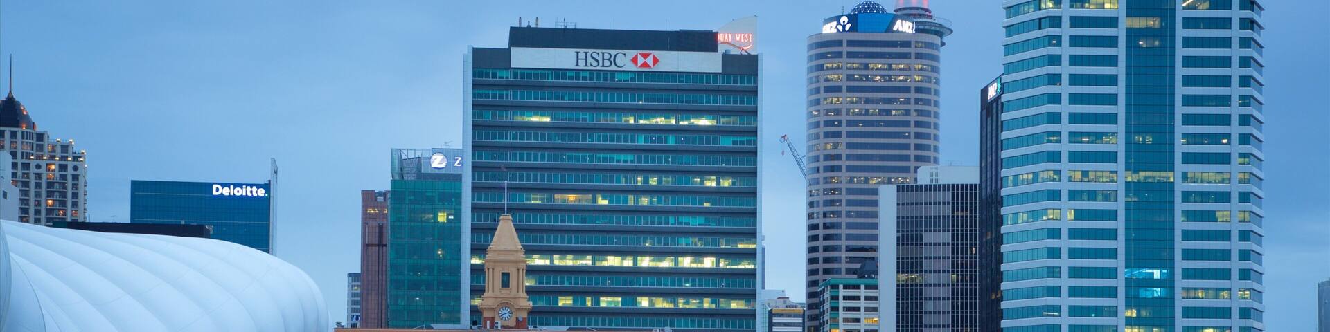 A waterfront with modern buildings, including HSBC and ANZ, and a large white structure.