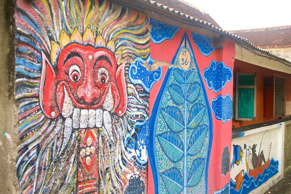 A colorful mural with a large face, a dragon, and a boat.