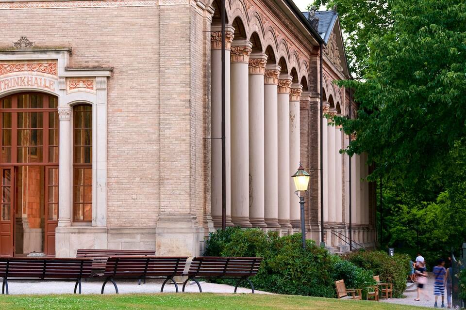 Een historisch gebouw met versierde zuilen en een grote houten deur.