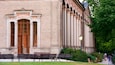 Un edificio histórico con columnas ornamentales y una puerta de madera grande.