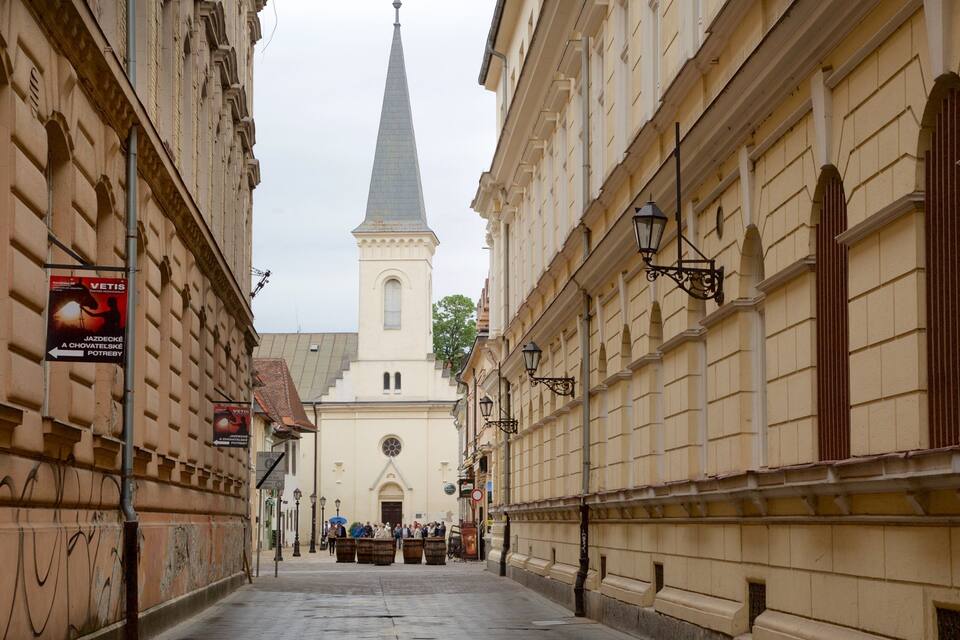 A street leading to a church with a tall spire.