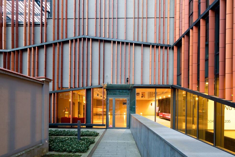 A modern building with vertical orange panels and a glass entrance.