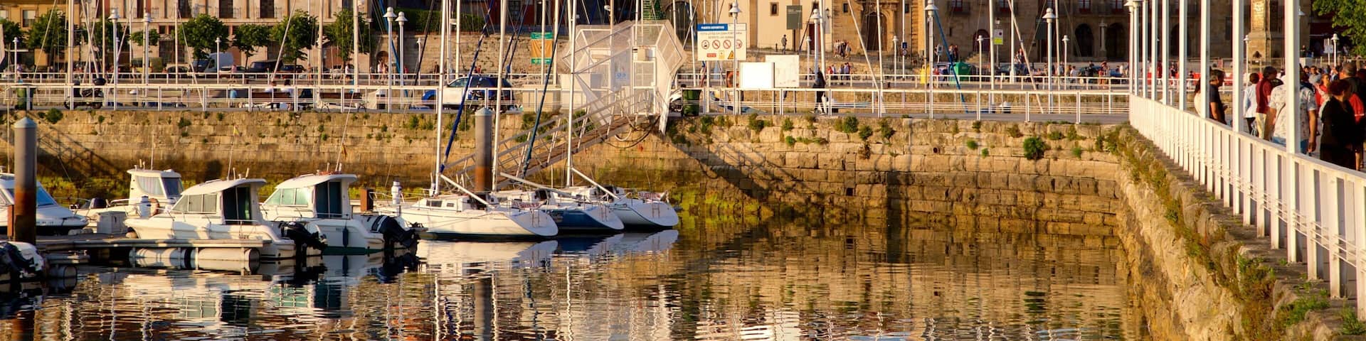 Gijon showing a sunset, a bay or harbour and a city