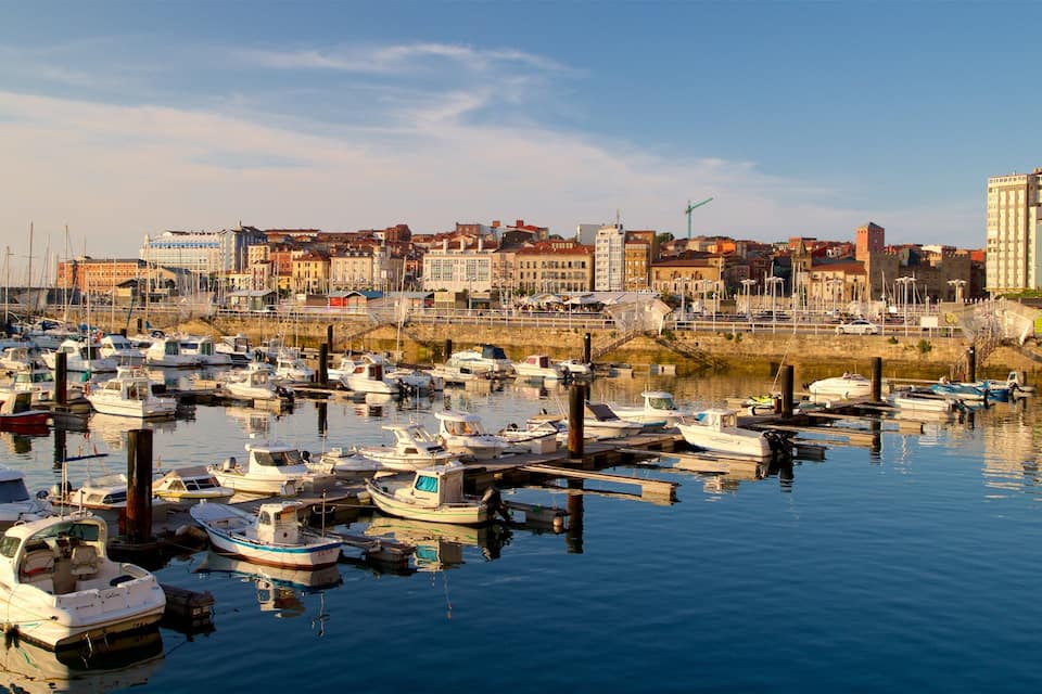 A marina filled with various boats, a cityscape with historic buildings, and a clear sky.