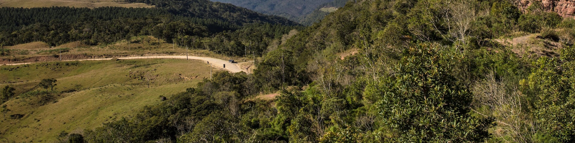 Un paisaje montañoso con cielo despejado, colinas ondulantes y una zona boscosa.