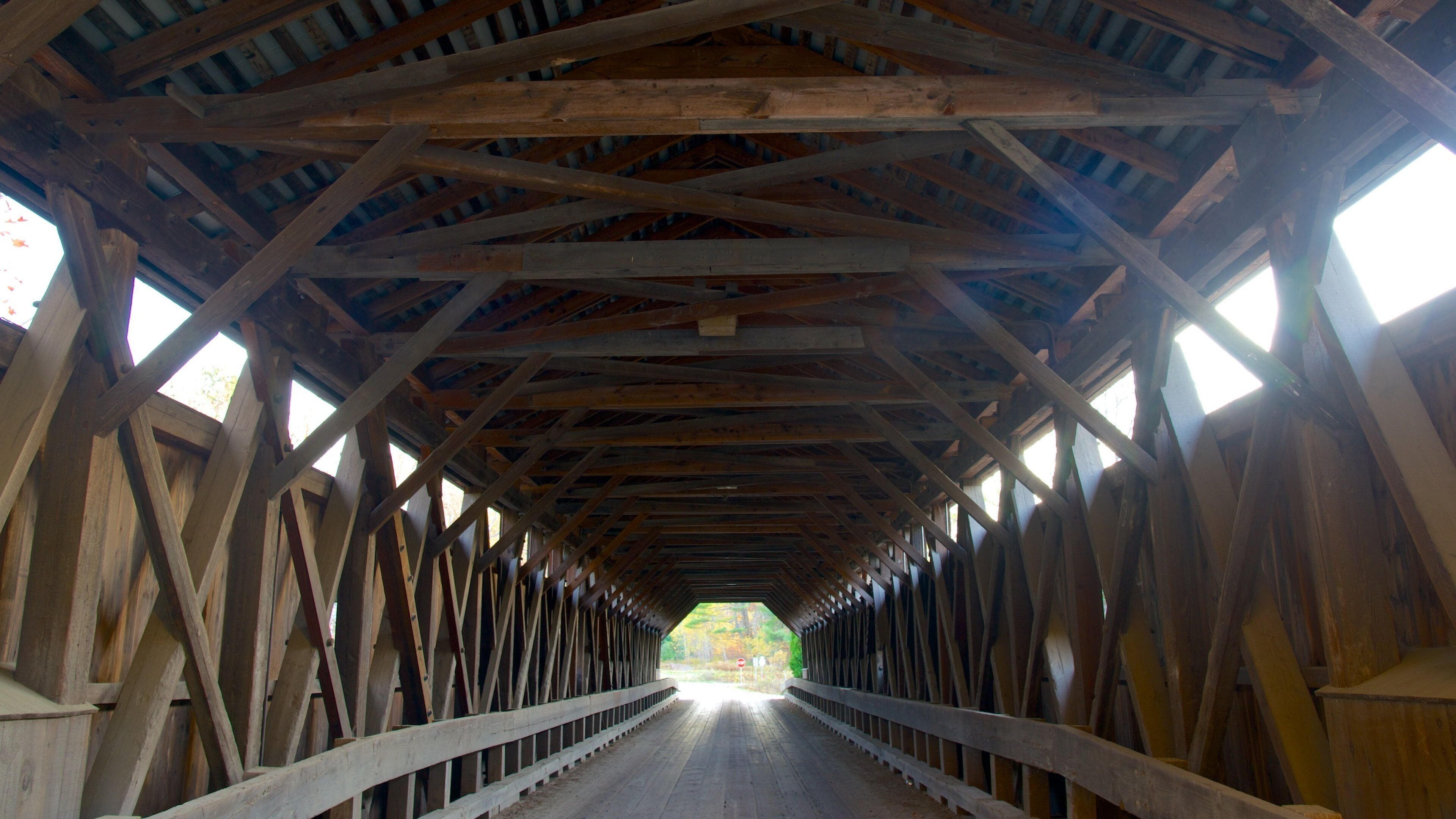 A wooden covered bridge with a truss structure and white railings.