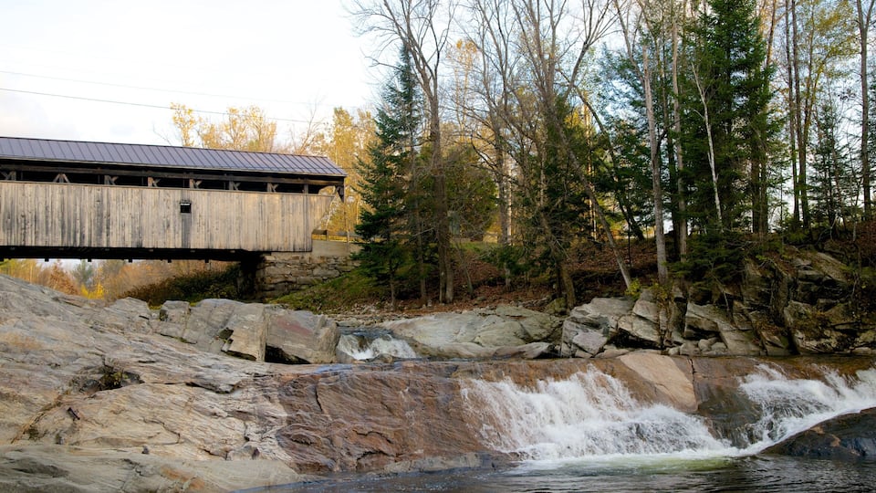 A wooden covered bridge over a rocky waterfall.