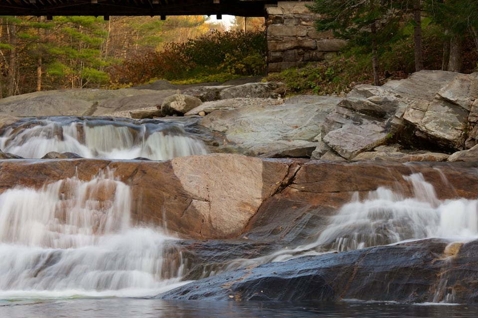 A waterfall cascading over large rocks in a forested area.