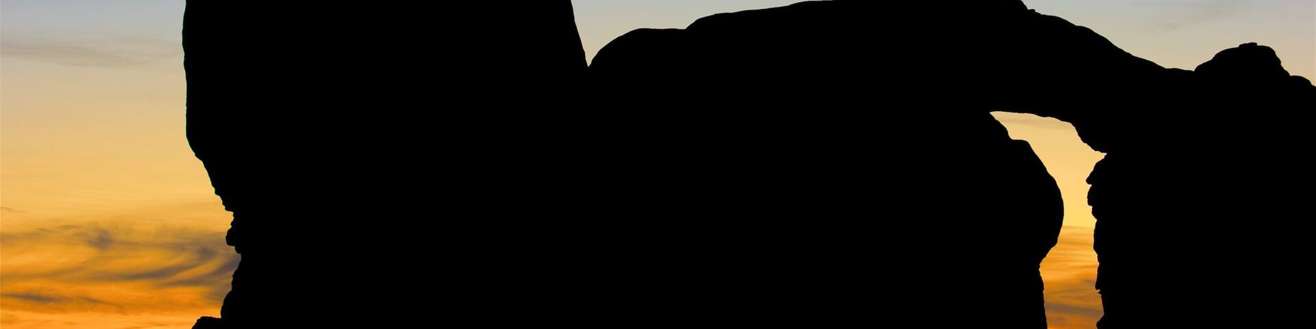 Una formación rocosa silueteada contra un cielo al atardecer.