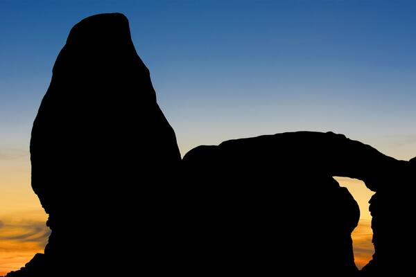 Eine Felsformation, silhouettiert vor einem Sonnenuntergangshimmel.