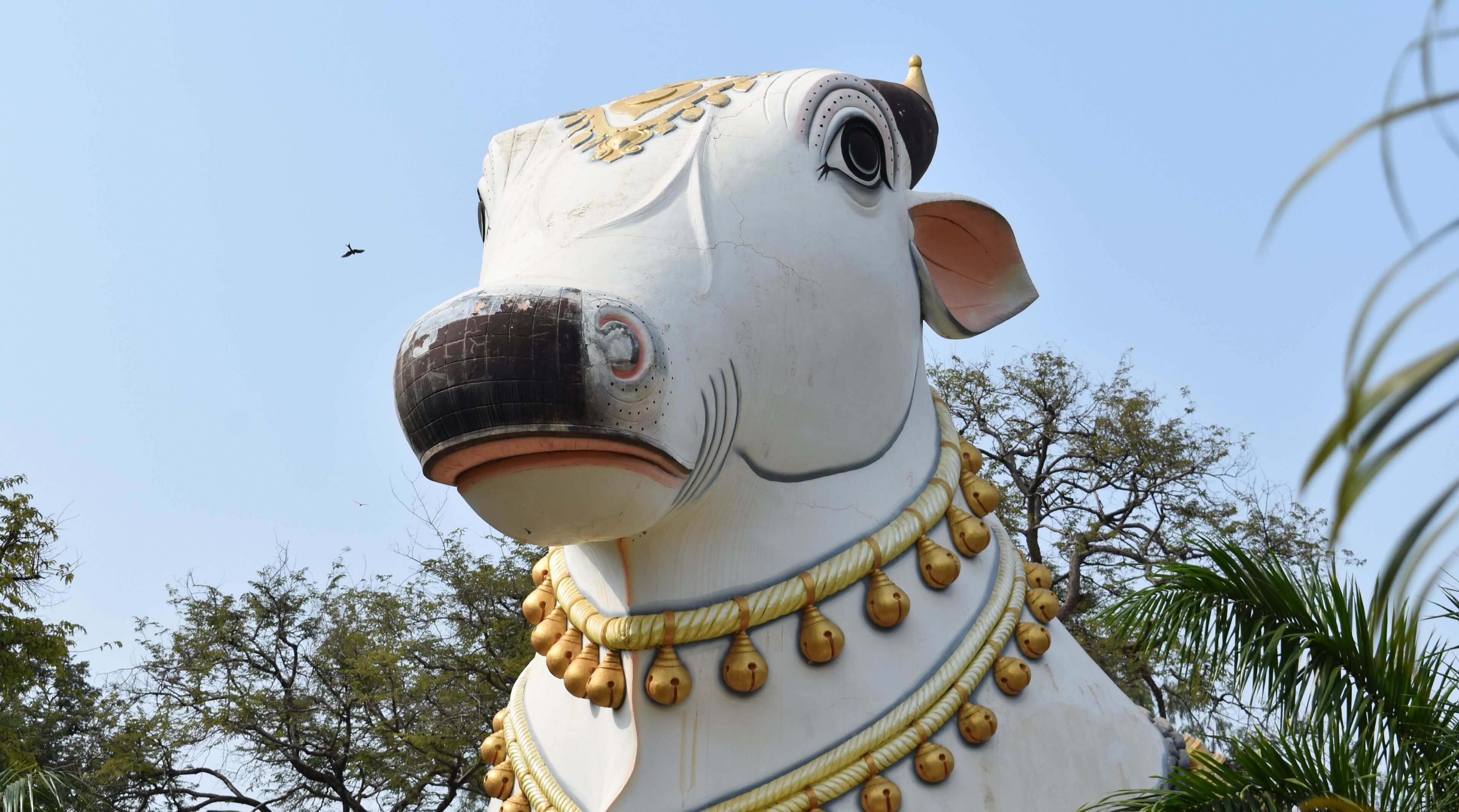 A large white statue of a cow with gold accents and a bell collar.