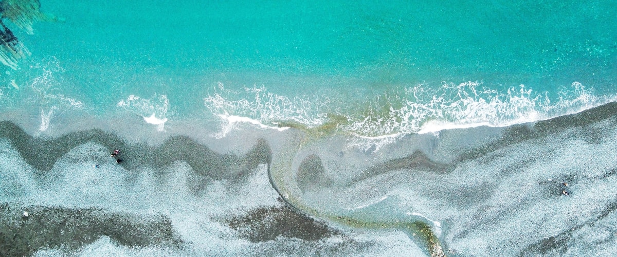 A turquoise ocean with waves crashing onto a sandy beach.