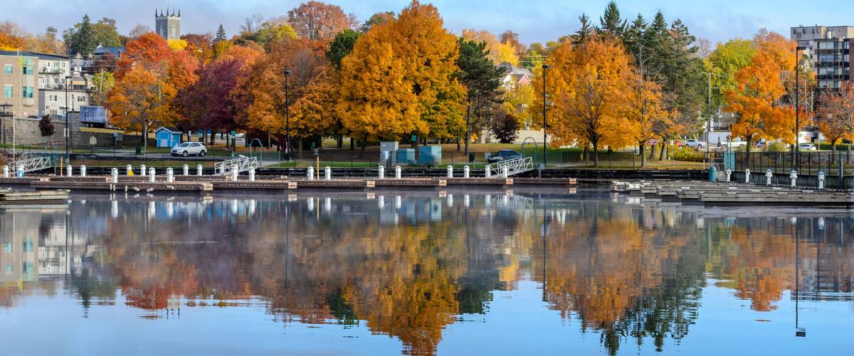 Un lago tranquillo che riflette alberi autunnali e il campanile di una chiesa in lontananza.