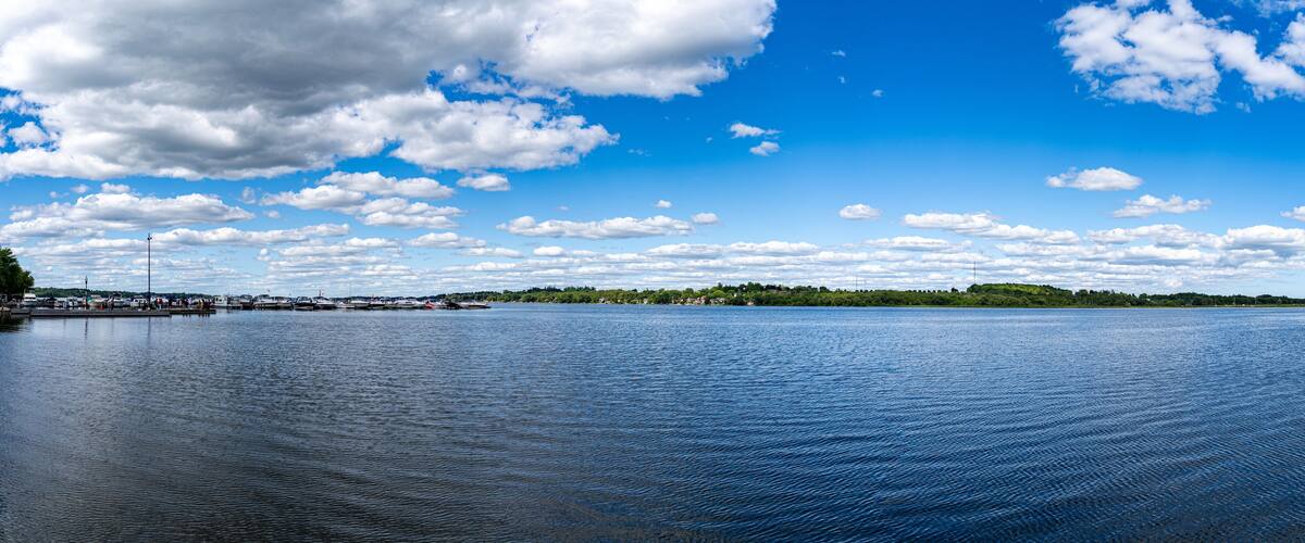 A calm lake with a clear sky and scattered clouds.